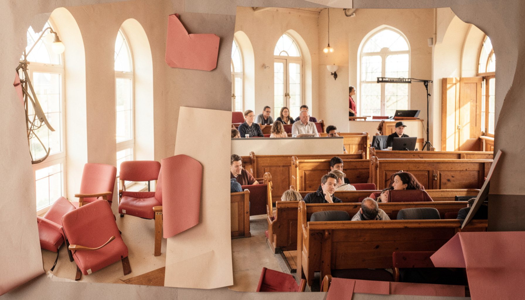 A warm-toned photograph of a lecture hall interior with wooden seating and tall arched windows, bathed in natural daylight